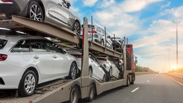 Car carrier truck loaded with white cars driving on a highway at sunset